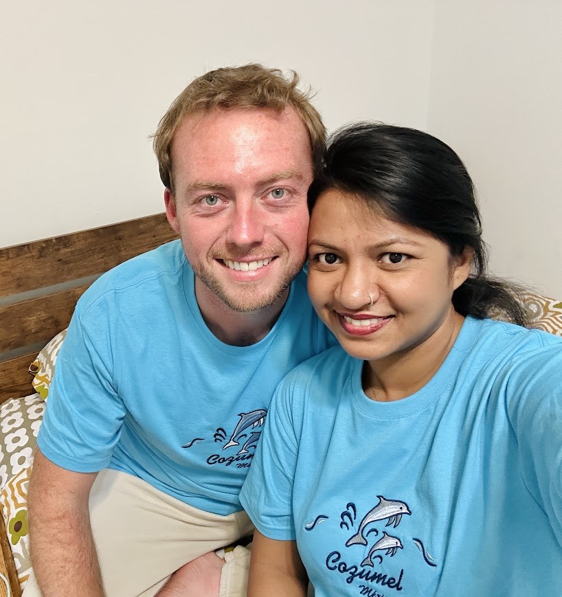 Adam and his wife Fahmida smiling together in matching blue shirts